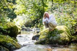 Frau sitzt auf Felsen im Pesenbachtal und genießt die Umgebung